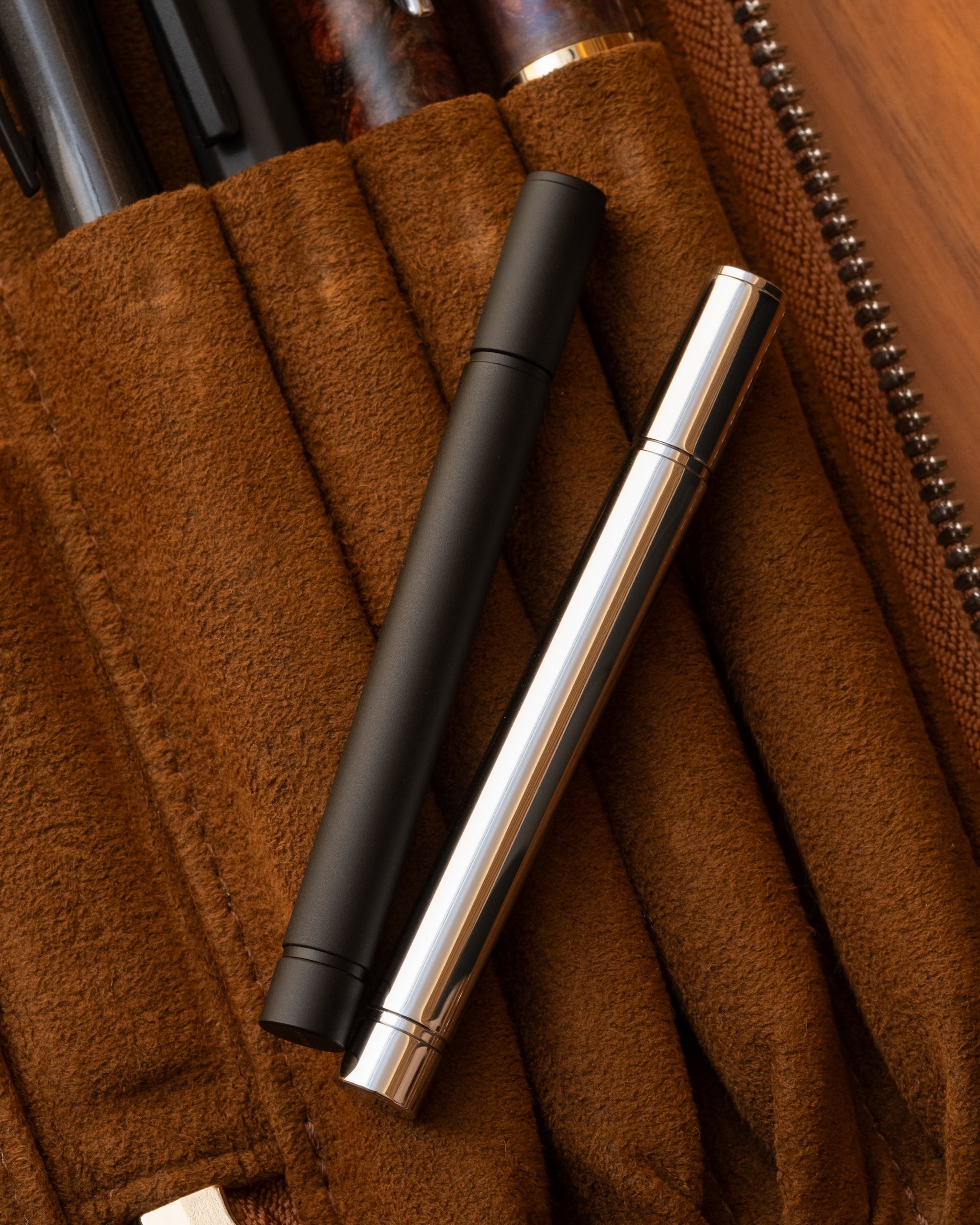 レザーペンケースDUCTの上に置かれたSEASAR DIJECT 芯ケース ブラックとシルバーのライフスタイルカット